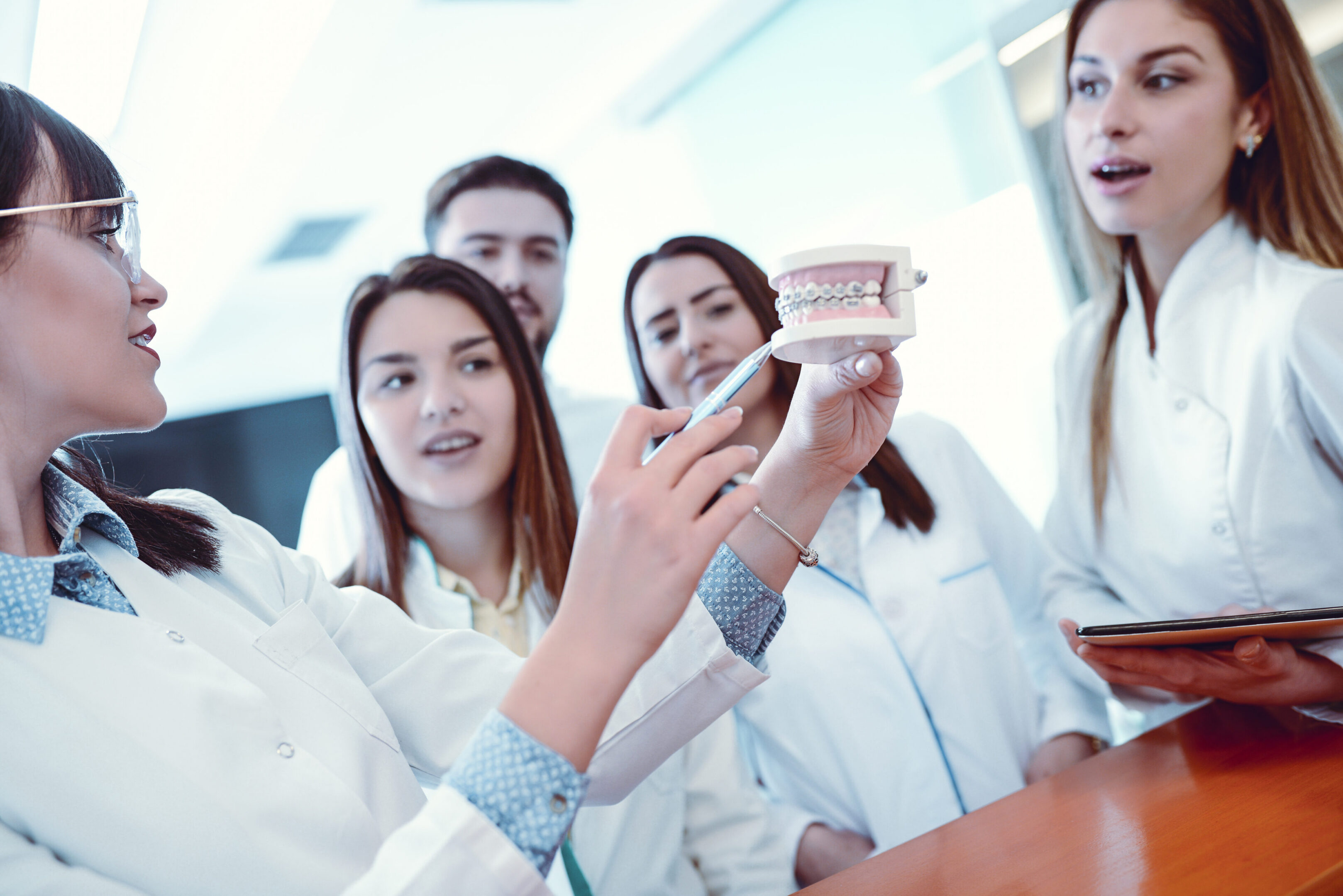 Group of dentists examining dental model.