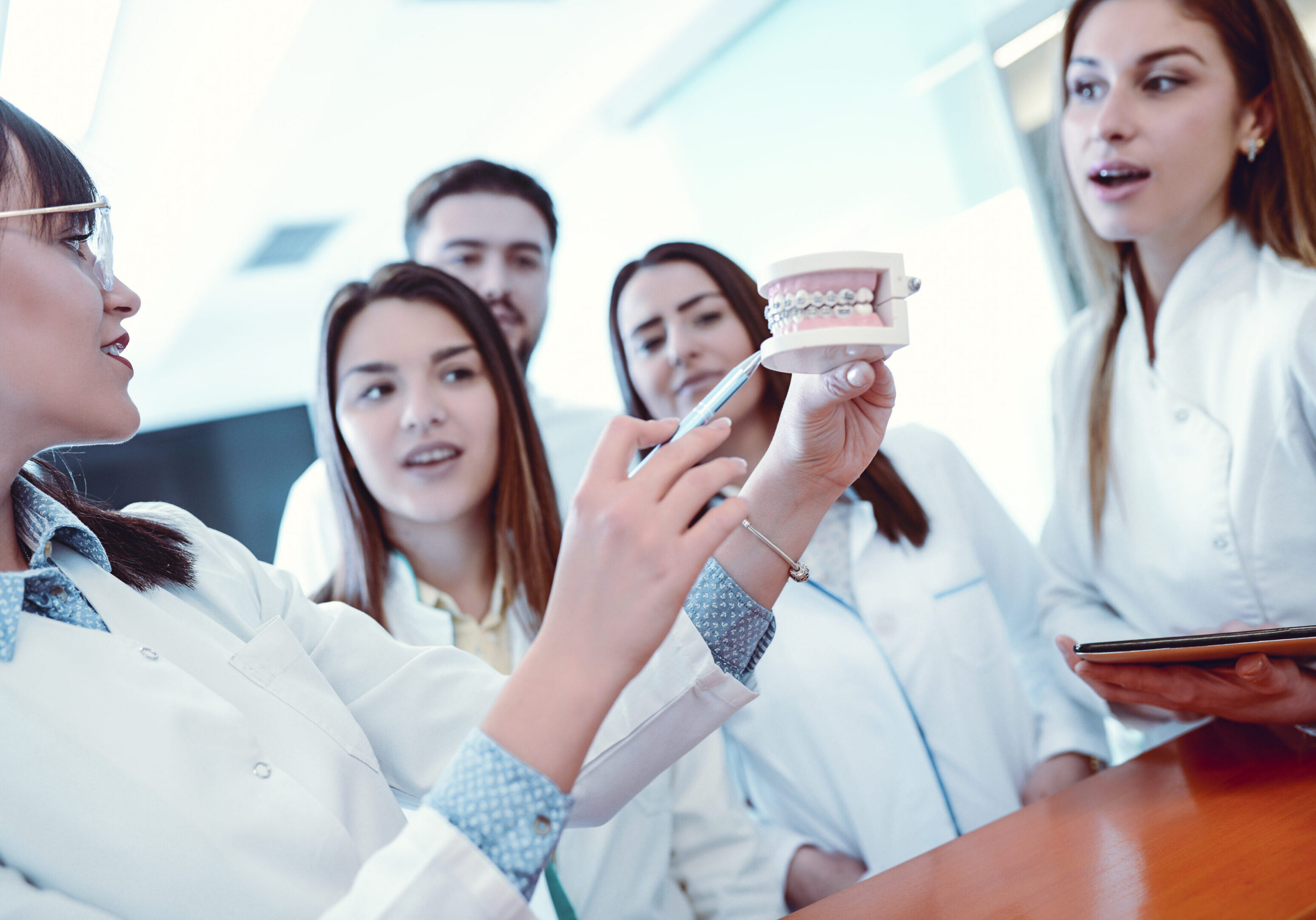Group of dentists examining dental model.